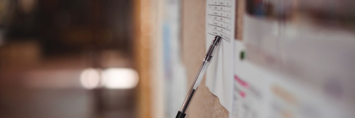 Stift zeigt auf einen Plan an einer Pinnwand