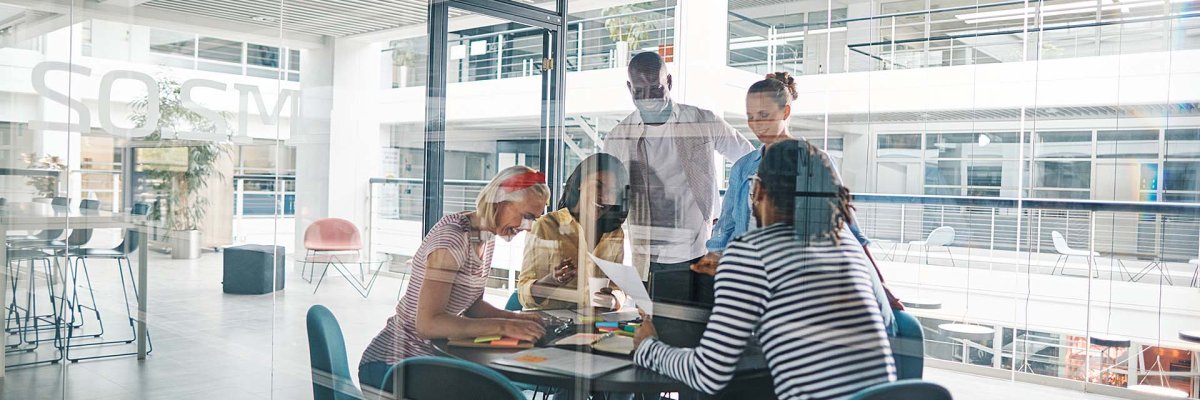 Laughing businesspeople working in a glass walled office boardroom