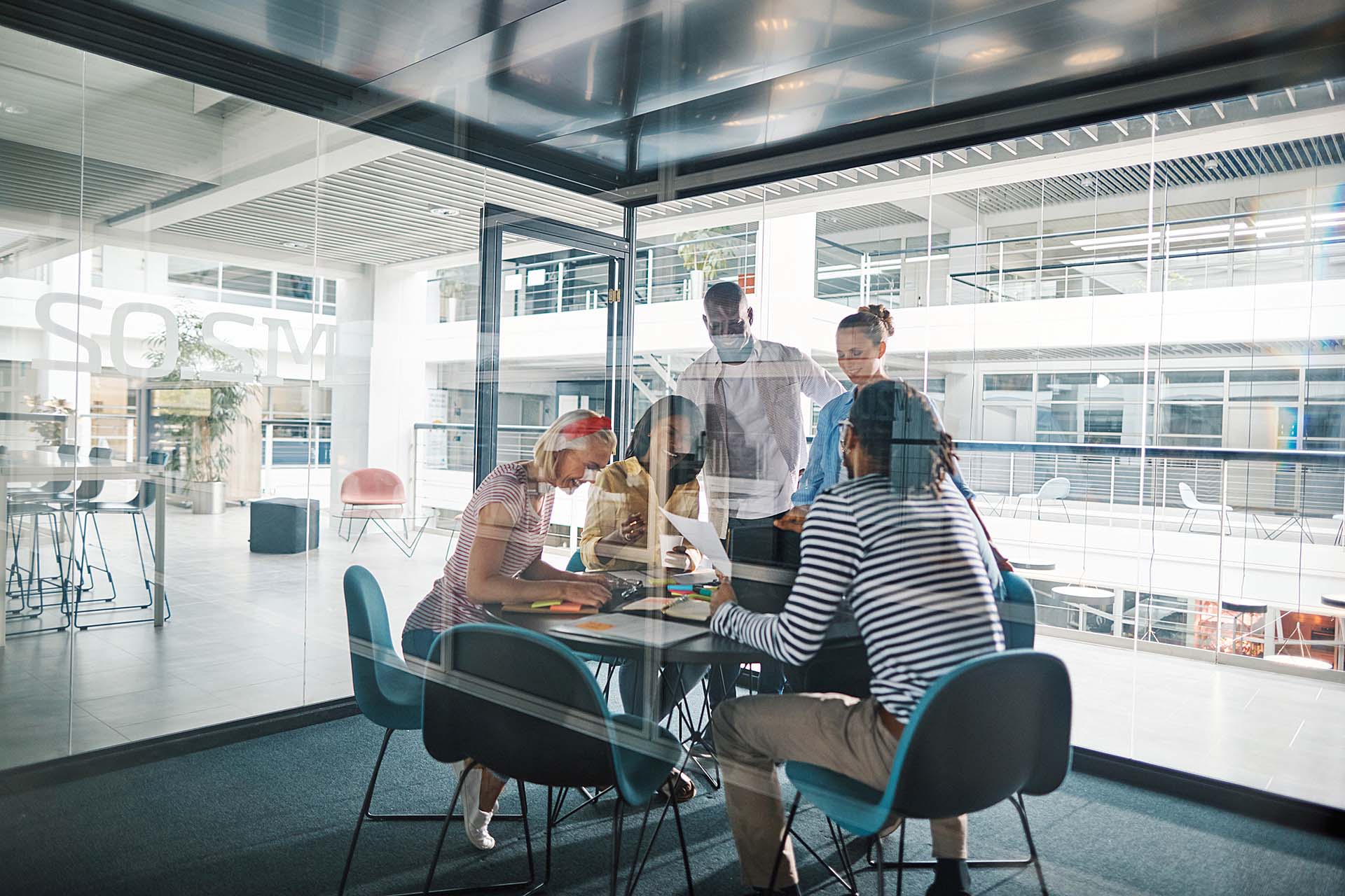 Laughing businesspeople working in a glass walled office boardroom