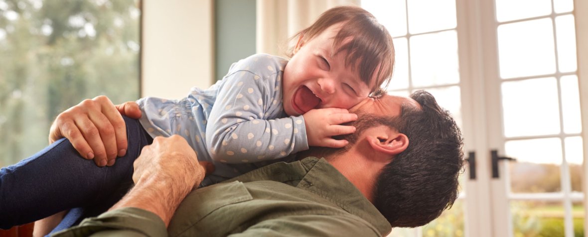Loving Father Playing With Laughing Down Syndrome Daughter At Home Together Loving Father Playing With Laughing Down Syndrome Daughter At Home Together