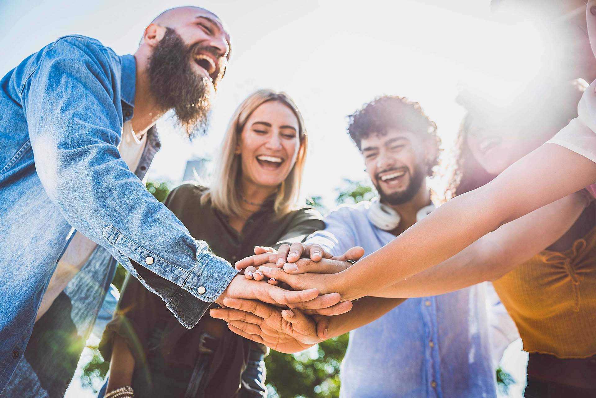 Multiracial happy young people stacking hands on top of each oth Multiracial happy young people stacking hands on top of each oth