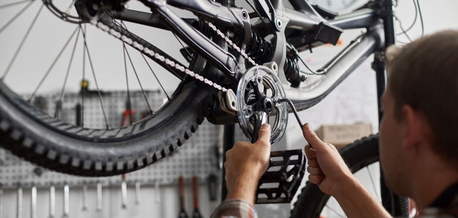 Male mechanic working in bicycle repair shop using tools
