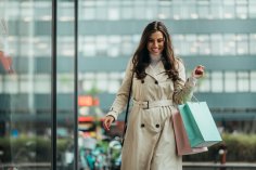 Young beautiful girl holding shopping bags while out in the city Junge Frau trägt Einkaufstasche in der Stadt