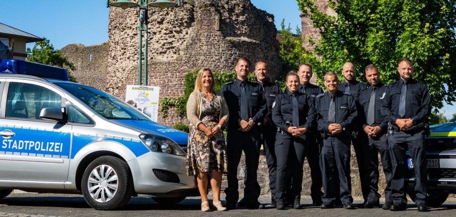 Gruppe der Stadtpolizei steht vor zwei Stadtpolizeiautos vor der Burg