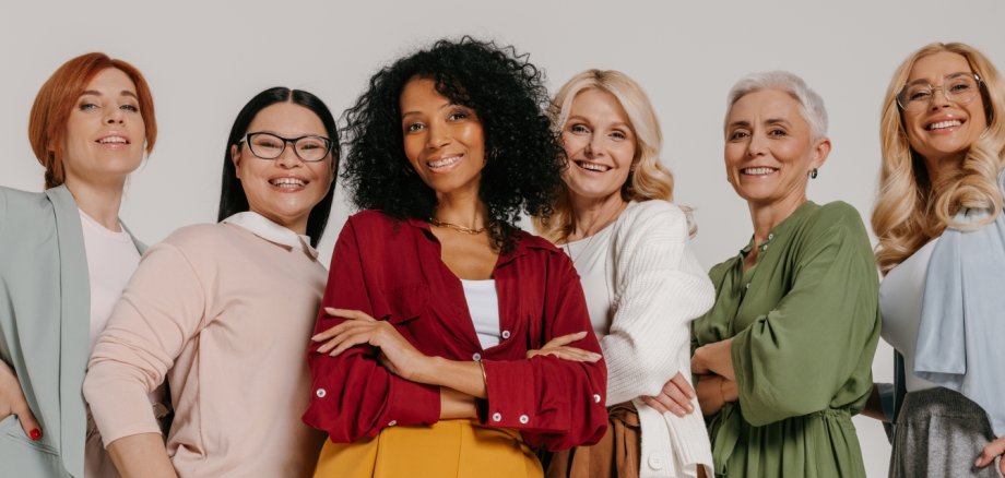 Group of elegant mature women bonding and smiling against grey background