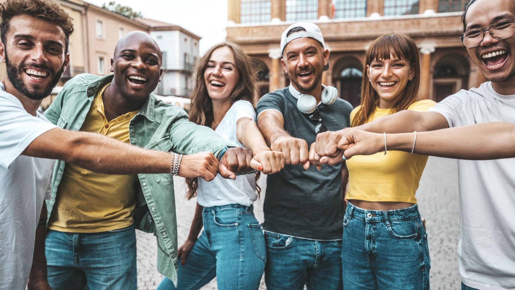 Multiracial group of young people making fist bump as symbol of
